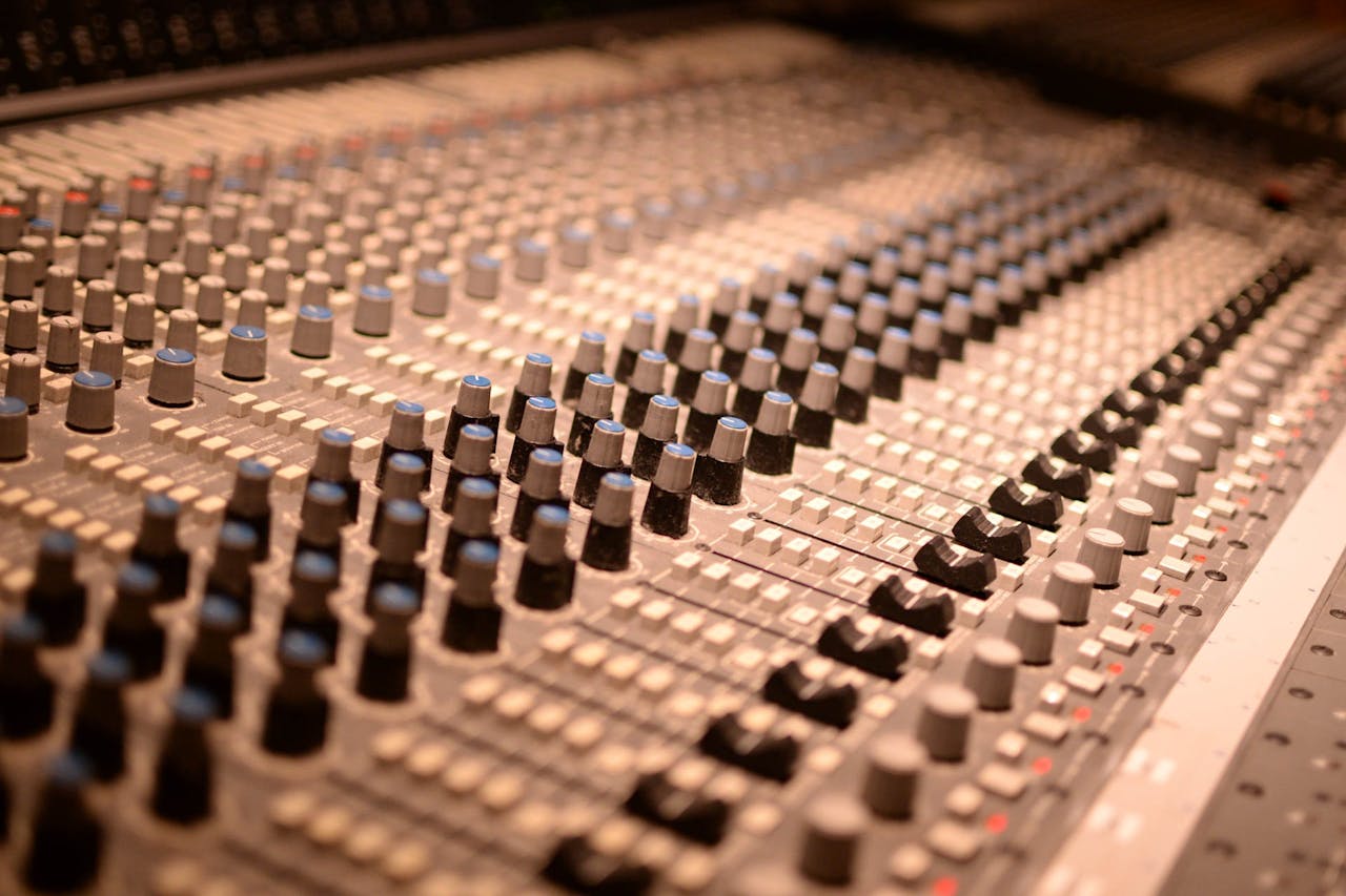 Detailed view of an analog audio mixing console with various knobs and sliders in a sound studio.